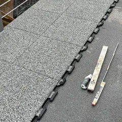 Na balkóně budou instalovány balkonové dlaždice WARCO z gumového granulátu. Skryté puzzle okraje zajišťují snadnou a přesnou pokládku. Vedle dlaždic jsou připraveny stahovací lať a metr k ověření rovnosti povrchu, který je utěsněn asfaltovou lepenkou.