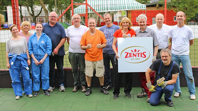After the work is done, a Zentis team lines up for a souvenir photo. The men and women stand on green WARCO flooring.